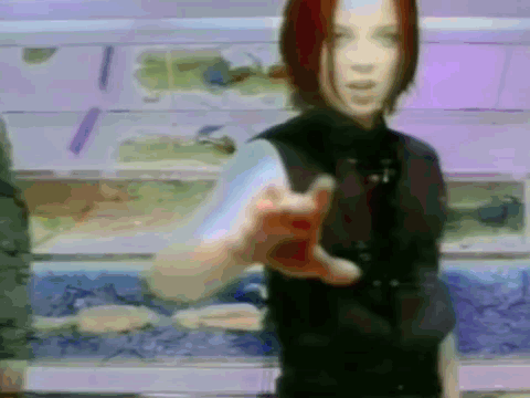 A Woman In A Black Vest Is Pointing At The Camera GIF