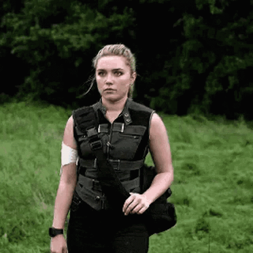 A Woman In A Black Vest Is Standing In A Field . GIF