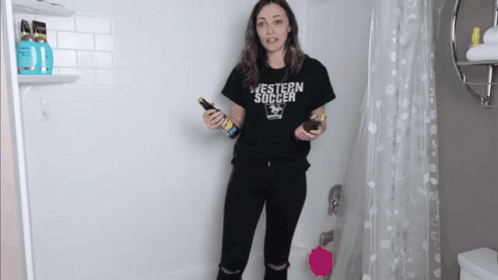 A Woman In A Black Western Soccer Shirt Holds A Bottle GIF