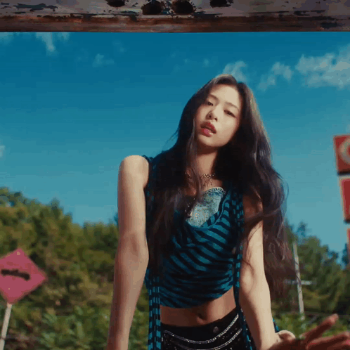 A Woman In A Blue And Black Striped Crop Top And Black Shorts GIF