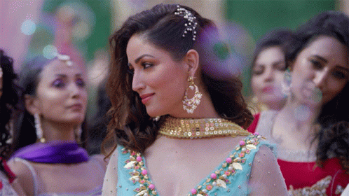 A Woman In A Blue And Gold Dress Stands In Front Of A Crowd Of Women GIF