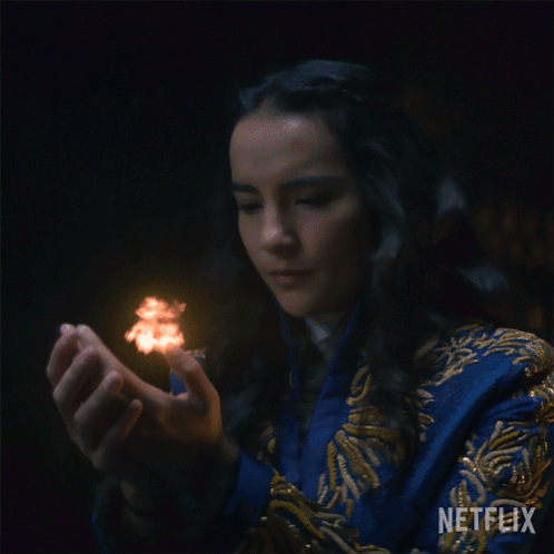 A Woman In A Blue And Gold Robe Is Holding A Glowing Ball In Her Hands With A Netflix Logo In The Corner GIF
