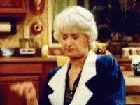 A Woman In A Blue And White Coat Is Sitting At A Table . GIF