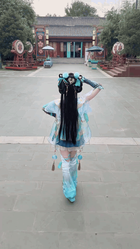 a woman in a blue and white costume is walking in front of a building