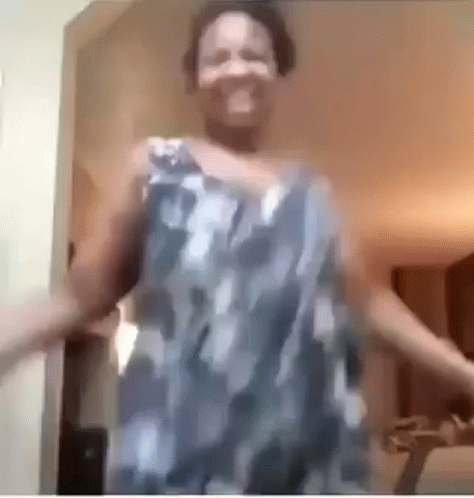 A Woman In A Blue And White Dress Is Dancing In A Room . GIF