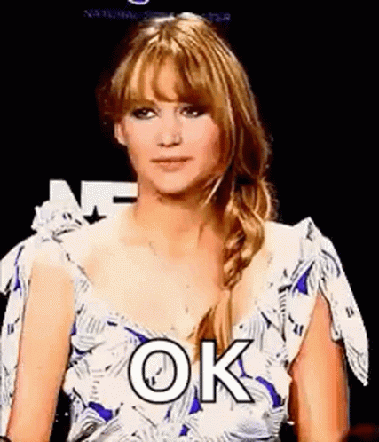 A Woman In A Blue And White Dress Is Making A Funny Face And Saying `` Ok '' . GIF