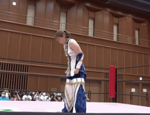 a woman in a blue and white outfit is standing on a ring