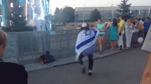 A Woman In A Blue And White Striped Shirt Is Dancing In Front Of A Crowd GIF
