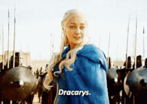 A Woman In A Blue Cape Is Standing In Front Of A Row Of Soldiers And Shields . GIF