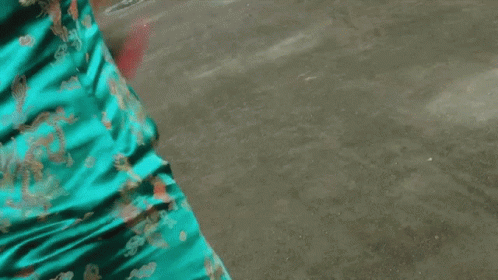 a woman in a blue cheongsam holds a sword