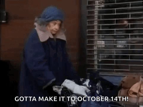A Woman In A Blue Coat Is Pushing A Shopping Cart With A Bag Of Clothes . GIF
