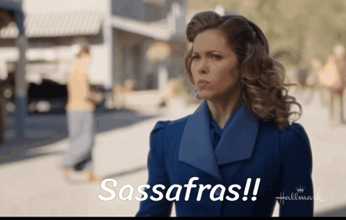 A Woman In A Blue Coat Says Sassafras On A Hallmark Ad GIF