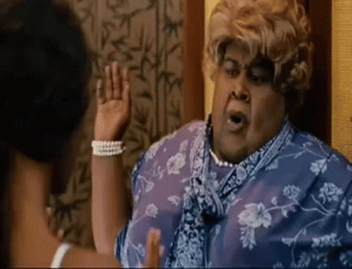 A Woman In A Blue Dress And Pearls Is Talking To Another Woman . GIF