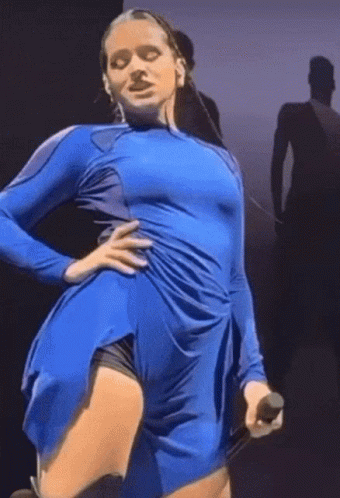 A Woman In A Blue Dress Holds A Microphone In Her Hand GIF