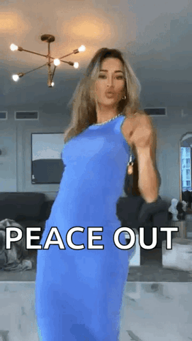 a woman in a blue dress is dancing in a living room with the words peace out written on the screen .
