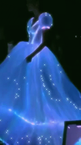 A Woman In A Blue Dress Is Dancing In Front Of A Computer Screen GIF