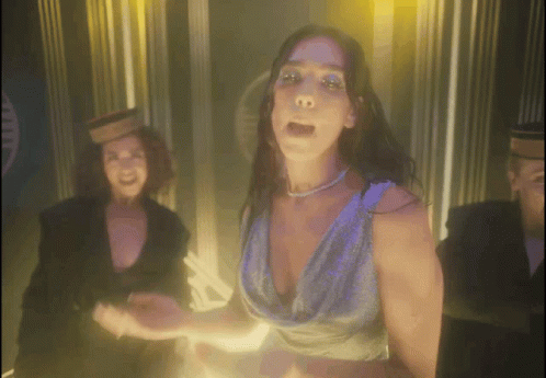 A Woman In A Blue Dress Is Dancing In Front Of A Man GIF
