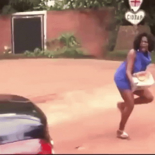 A Woman In A Blue Dress Is Dancing On The Side Of The Road . GIF