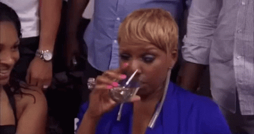 A Woman In A Blue Dress Is Drinking Water From A Glass . GIF