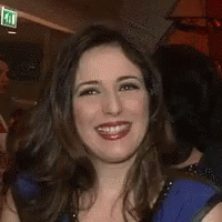 A Woman In A Blue Dress Is Holding A Microphone And Making A Funny Face . GIF