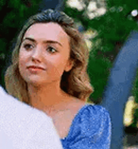 A Woman In A Blue Dress Is Looking Over Her Shoulder At A Man In A White Shirt . GIF