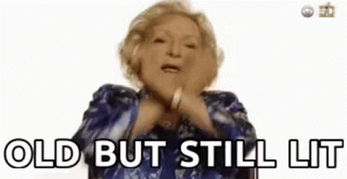 A Woman In A Blue Dress Is Making A Funny Face And Saying `` Old But Still Lit '' . GIF