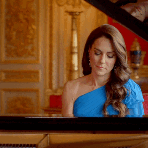 A Woman In A Blue Dress Is Playing The Piano GIF
