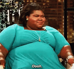A Woman In A Blue Dress Is Saying Oooh While Sitting In A Chair . GIF