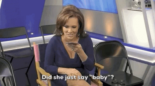 A Woman In A Blue Dress Is Sitting In A Chair Talking On A Cell Phone . GIF