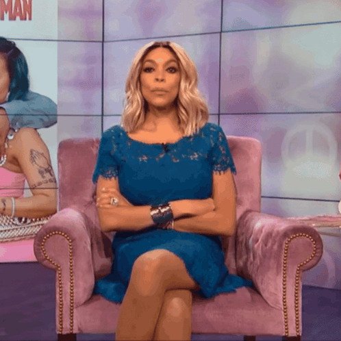 A Woman In A Blue Dress Is Sitting In A Pink Chair GIF