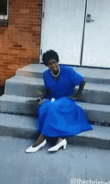 A Woman In A Blue Dress Is Sitting On The Steps GIF
