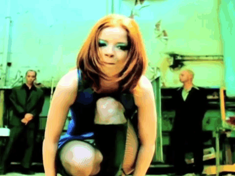 A Woman In A Blue Dress Is Squatting Down With A Man In A Suit Behind Her GIF