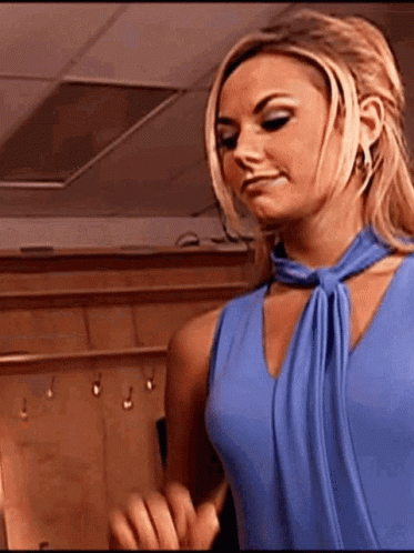 A Woman In A Blue Dress Is Standing In A Room And Making A Funny Face . GIF