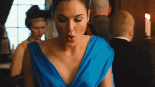 A Woman In A Blue Dress Is Standing In A Room With Her Mouth Open . GIF