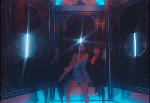 A Woman In A Blue Dress Is Standing In A Room With Two Other Women GIF