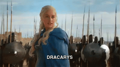 A Woman In A Blue Dress Is Standing In Front Of A Castle Surrounded By Soldiers And Shields . GIF