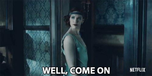 A Woman In A Blue Dress Is Standing In Front Of A Door And Says Well Come On GIF