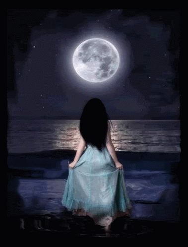 A Woman In A Blue Dress Is Standing In Front Of A Full Moon Over The Ocean GIF