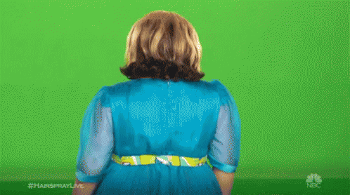 A Woman In A Blue Dress Is Standing In Front Of A Green Screen With Her Hands Outstretched . GIF