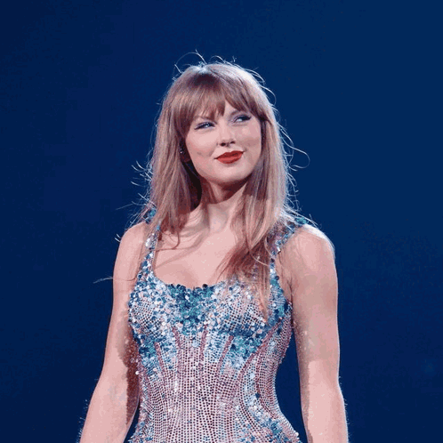 A Woman In A Blue Dress Is Standing In Front Of A Guitar Player GIF