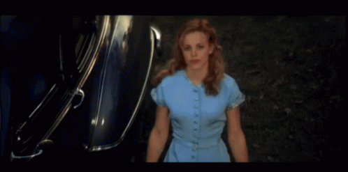 A Woman In A Blue Dress Is Standing In Front Of A Silver Car GIF