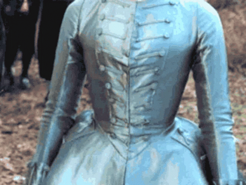 A Woman In A Blue Dress Is Standing In The Dirt GIF