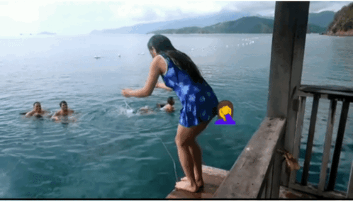 A Woman In A Blue Dress Is Standing On A Dock In The Ocean GIF