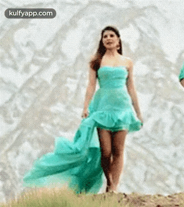 a woman in a blue dress is walking across a hill .
