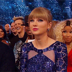 A Woman In A Blue Dress Stands In Front Of A Crowd Of People . GIF