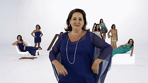 a woman in a blue dress stands in front of a group of women in different dresses