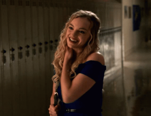 A Woman In A Blue Dress Stands In Front Of Lockers GIF