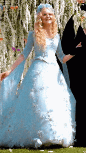 A Woman In A Blue Dress With A Blue Flower On Her Head GIF