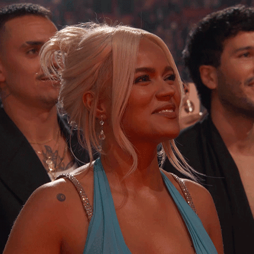A Woman In A Blue Dress With A Tattoo On Her Shoulder Smiles GIF