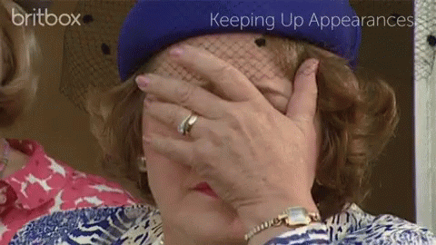 A Woman In A Blue Hat Covering Her Face With Her Hand GIF